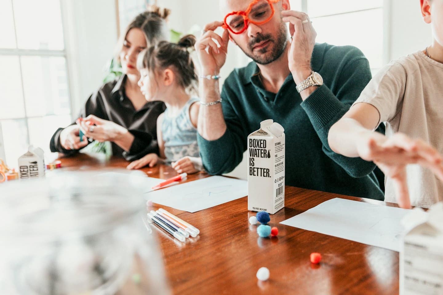 Family crafts together around a table with boxed water.